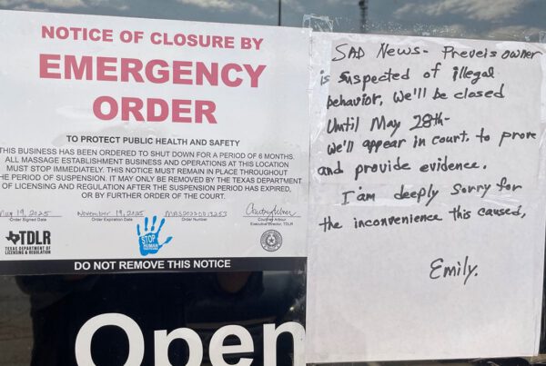Emergency closure notice from the Texas Department of Licensing and Regulation posted on a Lubbock massage parlor, citing a six-month shutdown due to public health and safety concerns amid a human trafficking investigation; handwritten sign beside it explains the closure is linked to suspected illegal behavior and announces a court appearance scheduled for May 28.