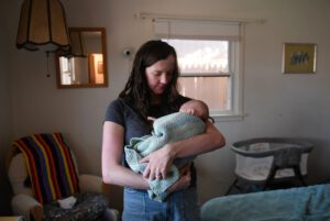 A mother in Lubbock, Texas, cradles her newborn son at home as measles cases rise in the region, prompting new parents to take extra precautions.