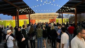 Crowd enjoying a live music performance under string lights at the First Friday Art Trail in Lubbock, Texas.