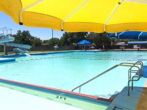 Empty Clapp Pool in Lubbock, Texas, under yellow umbrella during summer closure.