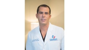 Dr. Juan Kurdi wearing a white lab coat with Caprock Cardiovascular Center logo.