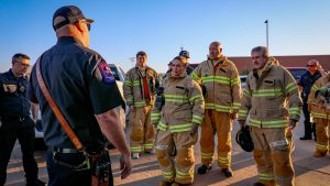 Lubbock firefighters in turnout gear receiving a safety briefing outdoors before training exercise.