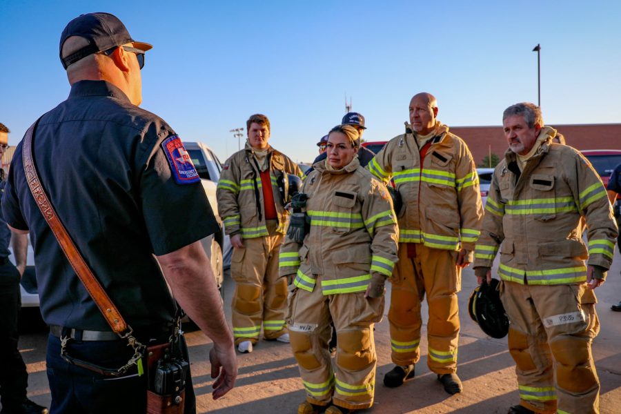 Lubbock firefighters in turnout gear receiving a safety briefing outdoors before training exercise.