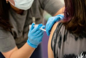 Healthcare worker administering a vaccine shot as Texas faces rising exemption requests and declining school immunization rates.
