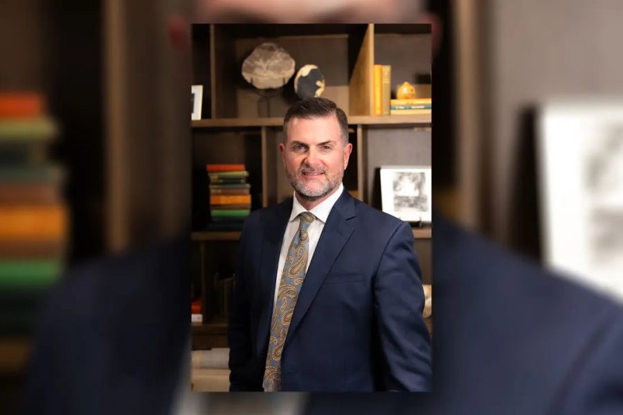 Brandon Creighton in a suit standing in front of bookshelves after being appointed Texas Tech University System Chancellor.