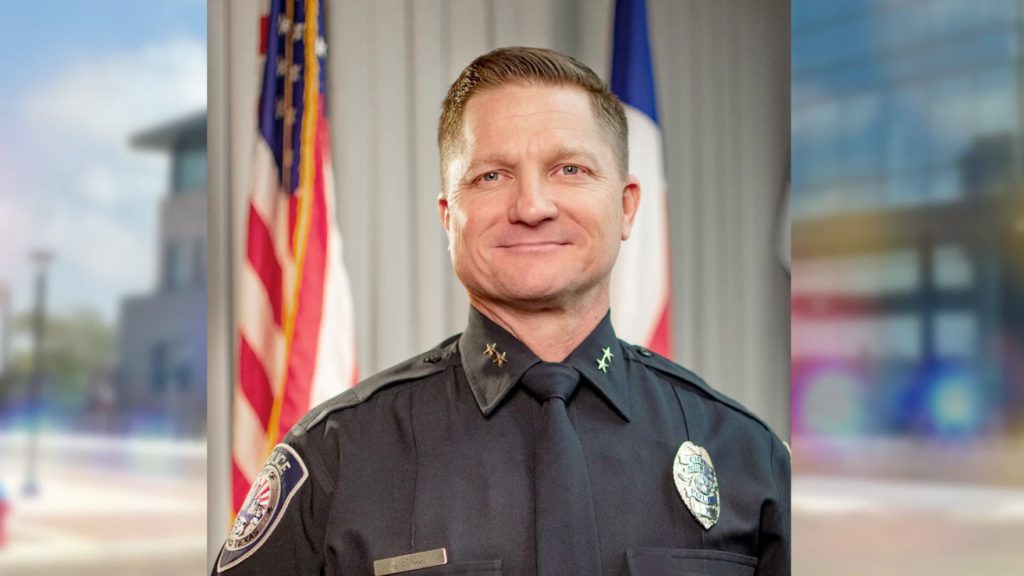 Seth Herman, Midland Police Chief and finalist for Lubbock’s next police chief, wearing his uniform and standing in front of U.S. and Texas flags.