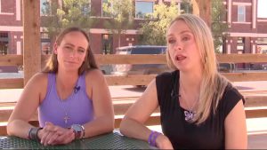 Two South Plains women sit at an outdoor table during a TV interview, discussing how the justice system failed to protect them from domestic violence.