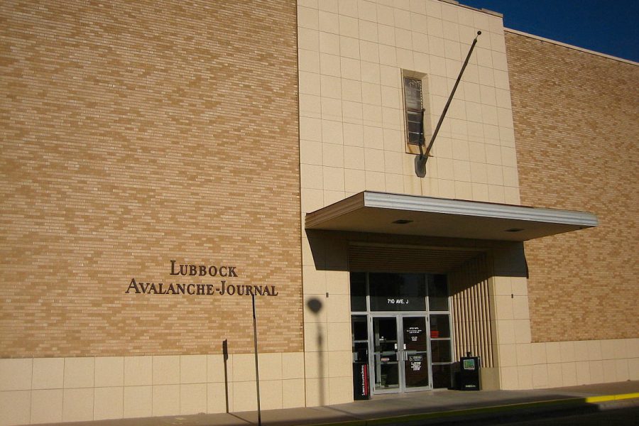 Exterior of the Lubbock Avalanche-Journal building on Avenue J, showing the newspaper’s brick facade and entrance under a clear Texas sky.