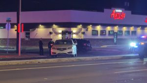 Police officers investigate a fatal hit-and-run at 50th Street and Canton Avenue outside Taqueria Awtlán in Lubbock, with patrol cars and emergency lights illuminating the scene at night.