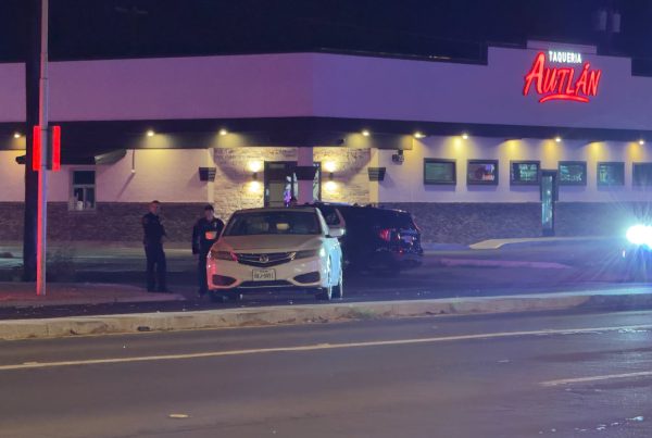 Police officers investigate a fatal hit-and-run at 50th Street and Canton Avenue outside Taqueria Awtlán in Lubbock, with patrol cars and emergency lights illuminating the scene at night.