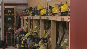 Rows of yellow helmets and turnout gear hanging in a Lubbock County volunteer fire station, highlighting funding cuts to local fire departments.