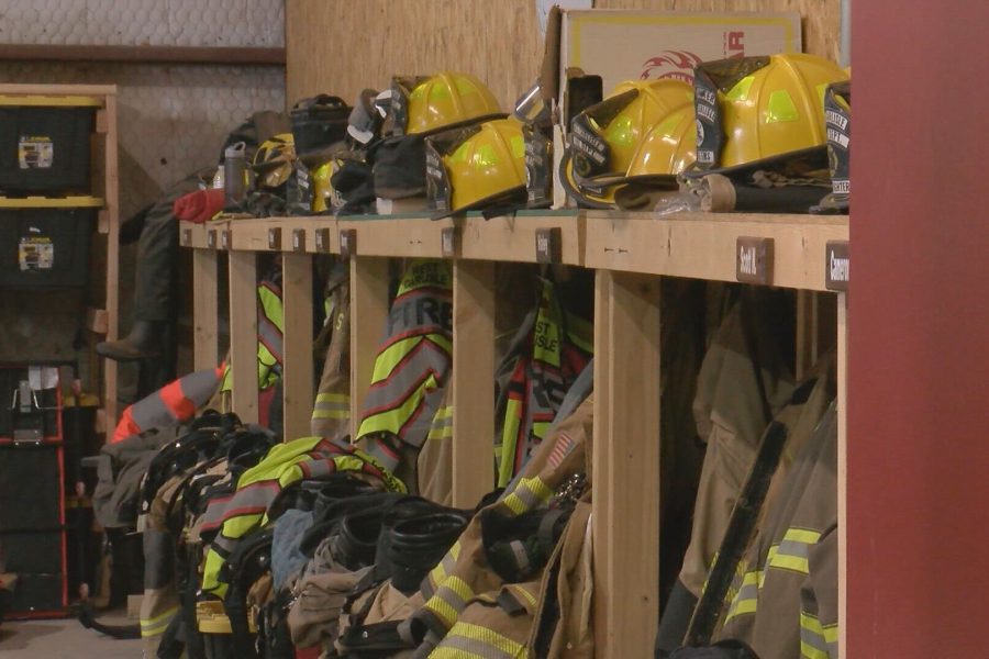 Rows of yellow helmets and turnout gear hanging in a Lubbock County volunteer fire station, highlighting funding cuts to local fire departments.