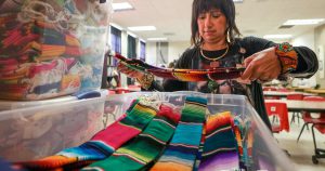 Dr. Maria Teresa Leos-Duemer inspects colorful serape stoles made by her Lubbock High School students for 600 Hispanic Texas Tech graduates, April 28, 2025.