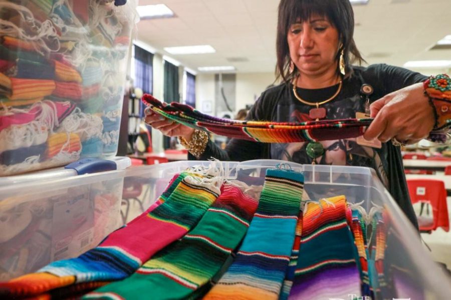Dr. Maria Teresa Leos-Duemer inspects colorful serape stoles made by her Lubbock High School students for 600 Hispanic Texas Tech graduates, April 28, 2025.