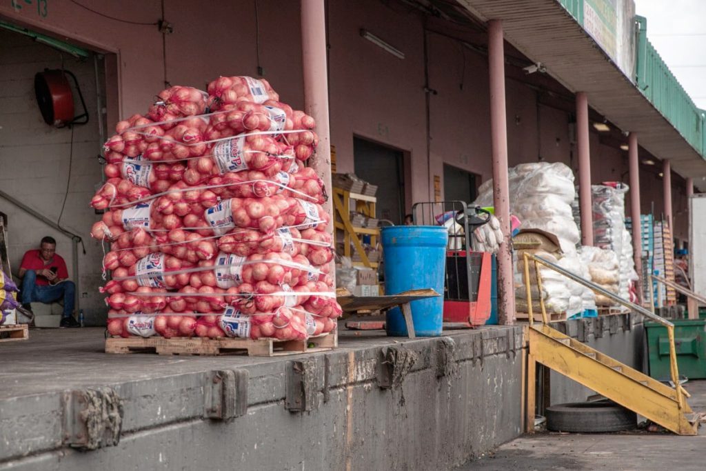 Stacks of bagged onions sit on a loading dock at a Texas grocery warehouse, illustrating how the SNAP benefits cutoff could leave perishable food unsold and strain small grocers across the state.