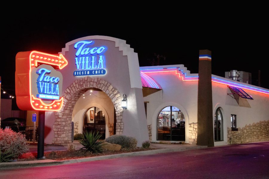 Exterior of Taco Villa in Lubbock, Texas at night, featuring neon red and blue lights on the stucco building and a glowing retro arrow sign.