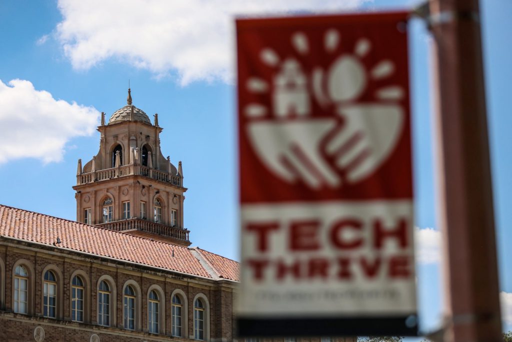 Texas Tech University administration building with “Tech Thrive” banner in foreground on a sunny day in Lubbock, Texas.