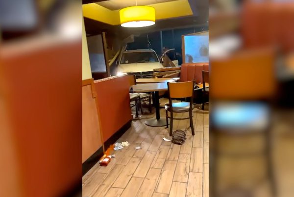 Interior of a Lubbock Denny’s on Slide Road after a car crashed through the wall, showing the vehicle inside the dining area with broken booths, scattered debris, and chairs knocked over.