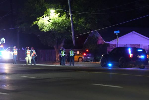 Police lights and utility crews on Slide Road at night after a car chase ended in a crash with a pole and tree in Lubbock.