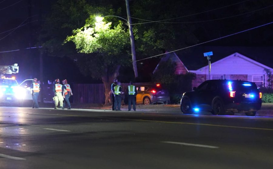 Police lights and utility crews on Slide Road at night after a car chase ended in a crash with a pole and tree in Lubbock.