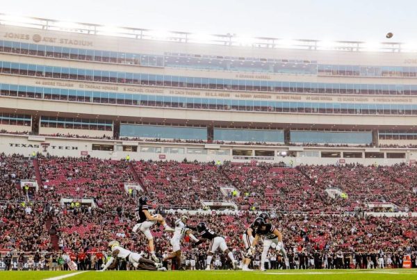Texas Tech football players in action during a game at Jones AT&T Stadium with a packed crowd in the stands.