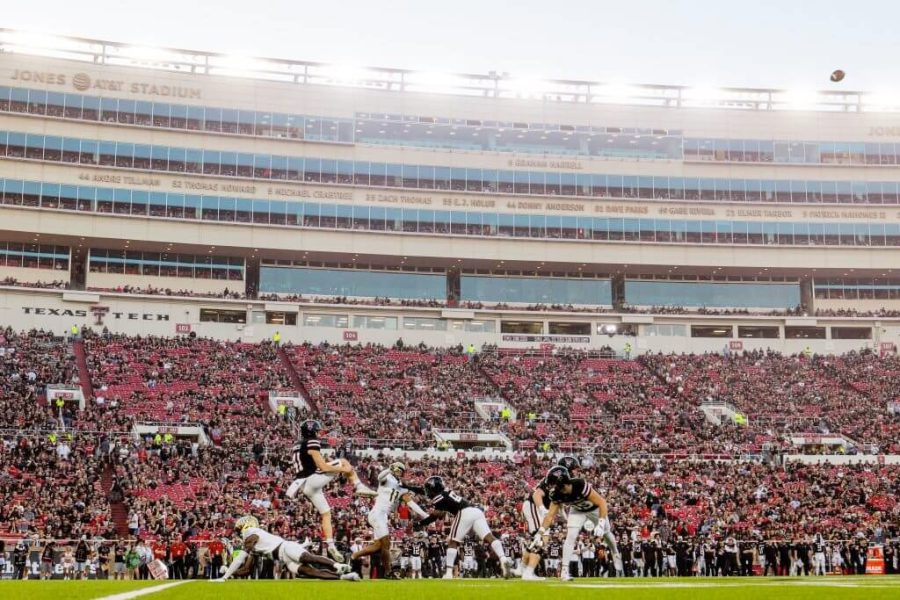 Texas Tech football players in action during a game at Jones AT&T Stadium with a packed crowd in the stands.