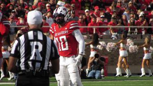 Texas Tech Red Raiders linebacker on the field during a home game as fans and cheerleaders fill the stands in Lubbock, Texas.
