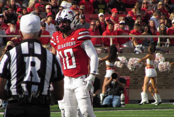 Texas Tech Red Raiders linebacker on the field during a home game as fans and cheerleaders fill the stands in Lubbock, Texas.