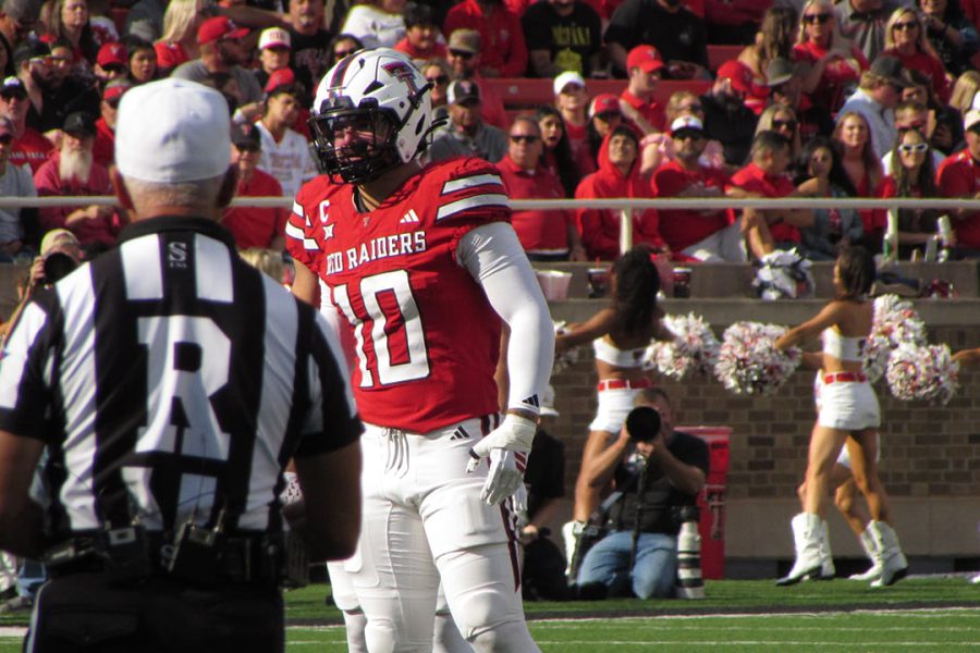 Texas Tech Red Raiders linebacker on the field during a home game as fans and cheerleaders fill the stands in Lubbock, Texas.