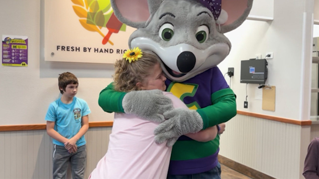 Carilyn “Cari” Truelock hugging the Chuck E. Cheese mascot during her surprise anti-bullying celebration in Lubbock, surrounded by supportive students.