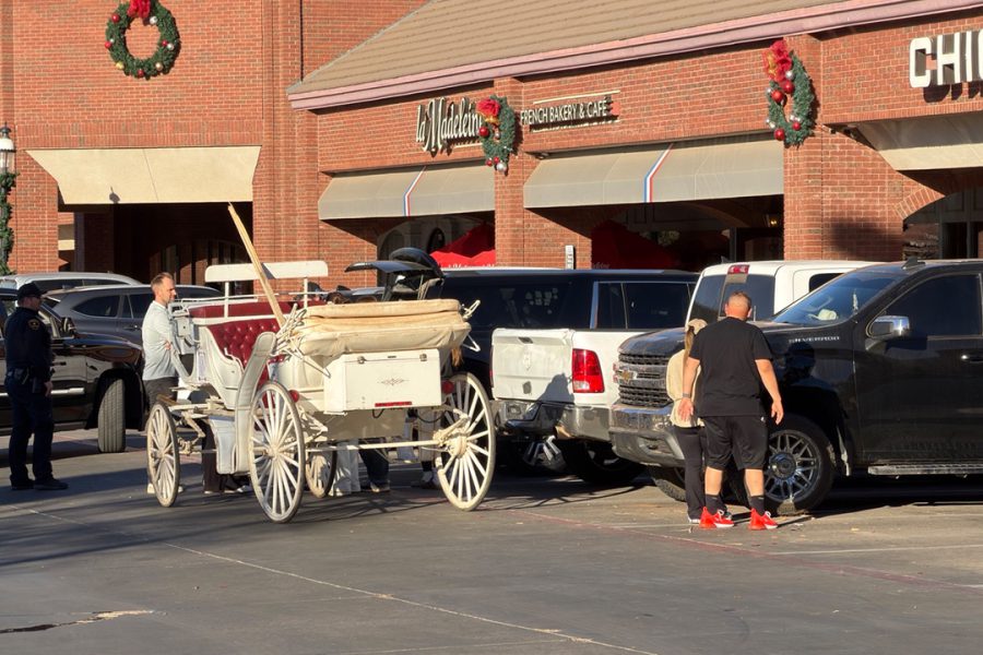 Horse-drawn Christmas carriage involved in a crash with parked vehicles at Kingsgate Center in Lubbock, Texas, as bystanders and police look on.