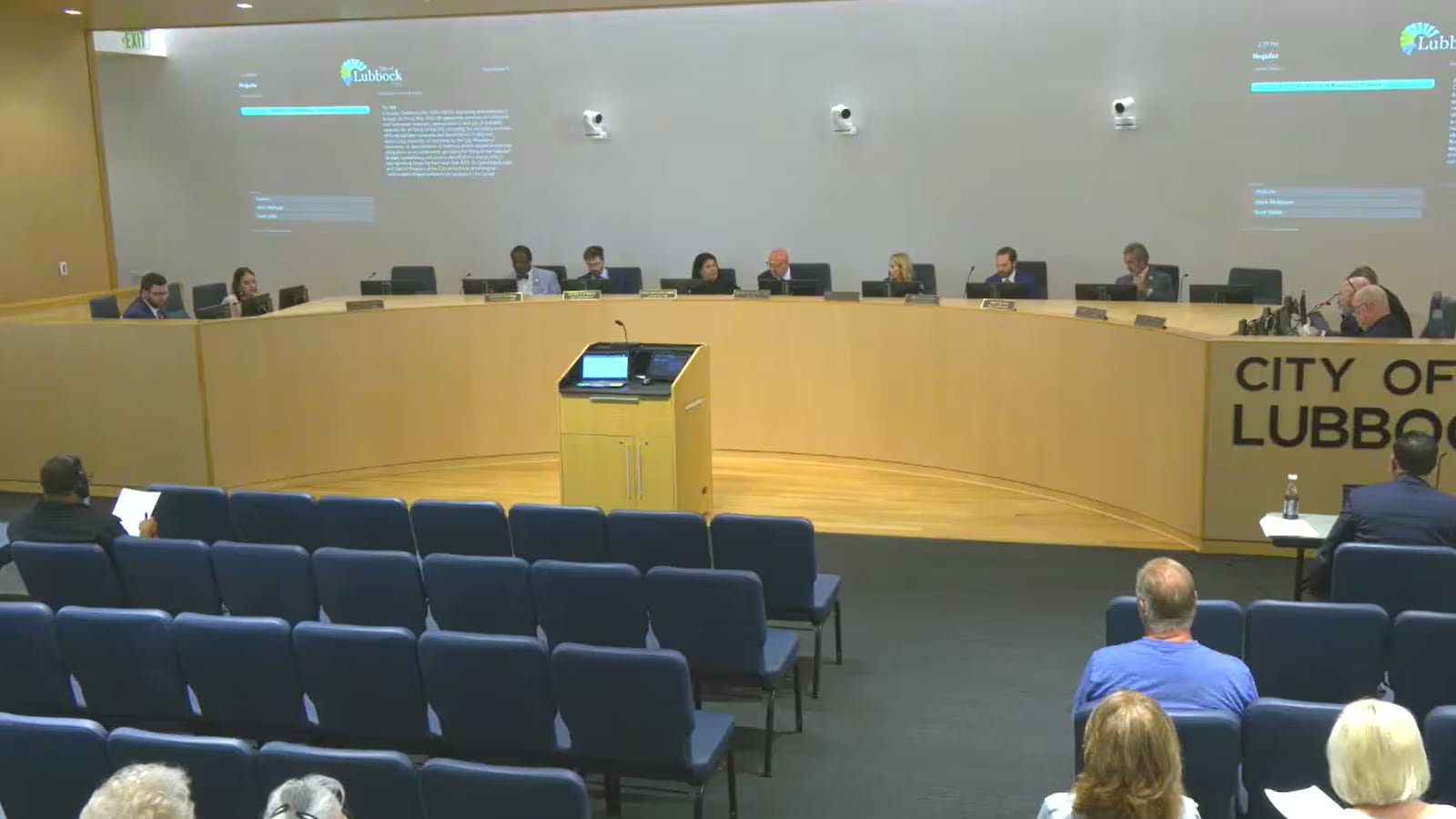 Wide view of the Lubbock City Council chamber during a public meeting, showing council members seated at the front and a few attendees in the audience.