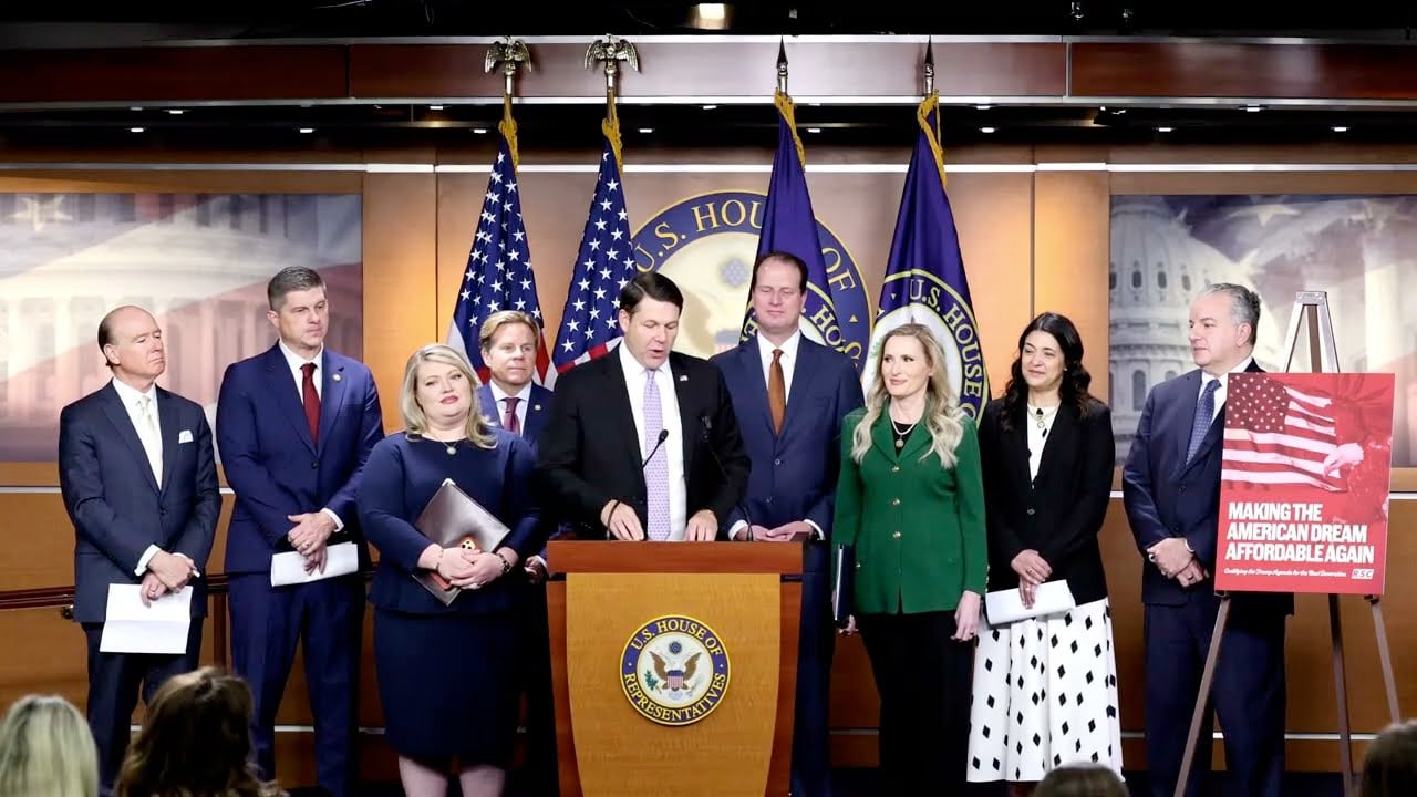 Members of Congress stand at a U.S. House podium during a press conference promoting an affordability-focused economic agenda, with American flags and a sign reading "Making the American Dream Affordable Again" in the background..