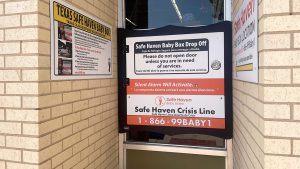 Safe Haven Baby Box installed at Lubbock Fire Station 9 with signage explaining anonymous infant surrender and crisis hotline information.