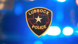 Lubbock Police Department badge illuminated against flashing blue and red patrol lights at night.