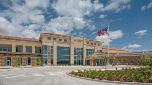 Exterior of the VA Lubbock Clinic in West Texas, a modern government healthcare building serving regional veterans under a blue sky with an American flag flying.