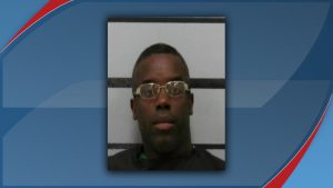 A mugshot of Charles Deeundray Green, who was arrested in Lubbock, Texas, on February 2, 2026, for multiple charges including aggravated assault with a deadly weapon. He is wearing gold-rimmed glasses and a dark shirt.