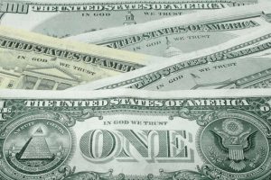 A close-up, overlapping stack of United States one-dollar bills, showing the reverse side with the Great Seal and the word "ONE" prominently displayed.