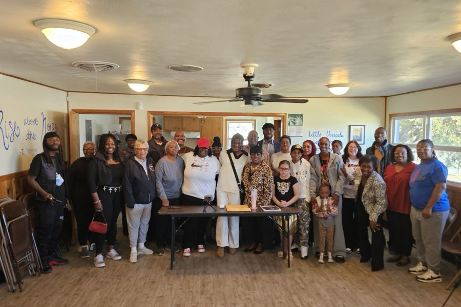 A group of approximately 25 community members, including representatives from the NAACP and the Lubbock Coalition of Black Democrats, stand together in a wood-paneled room for a press conference supporting student DeTayevion Lang.