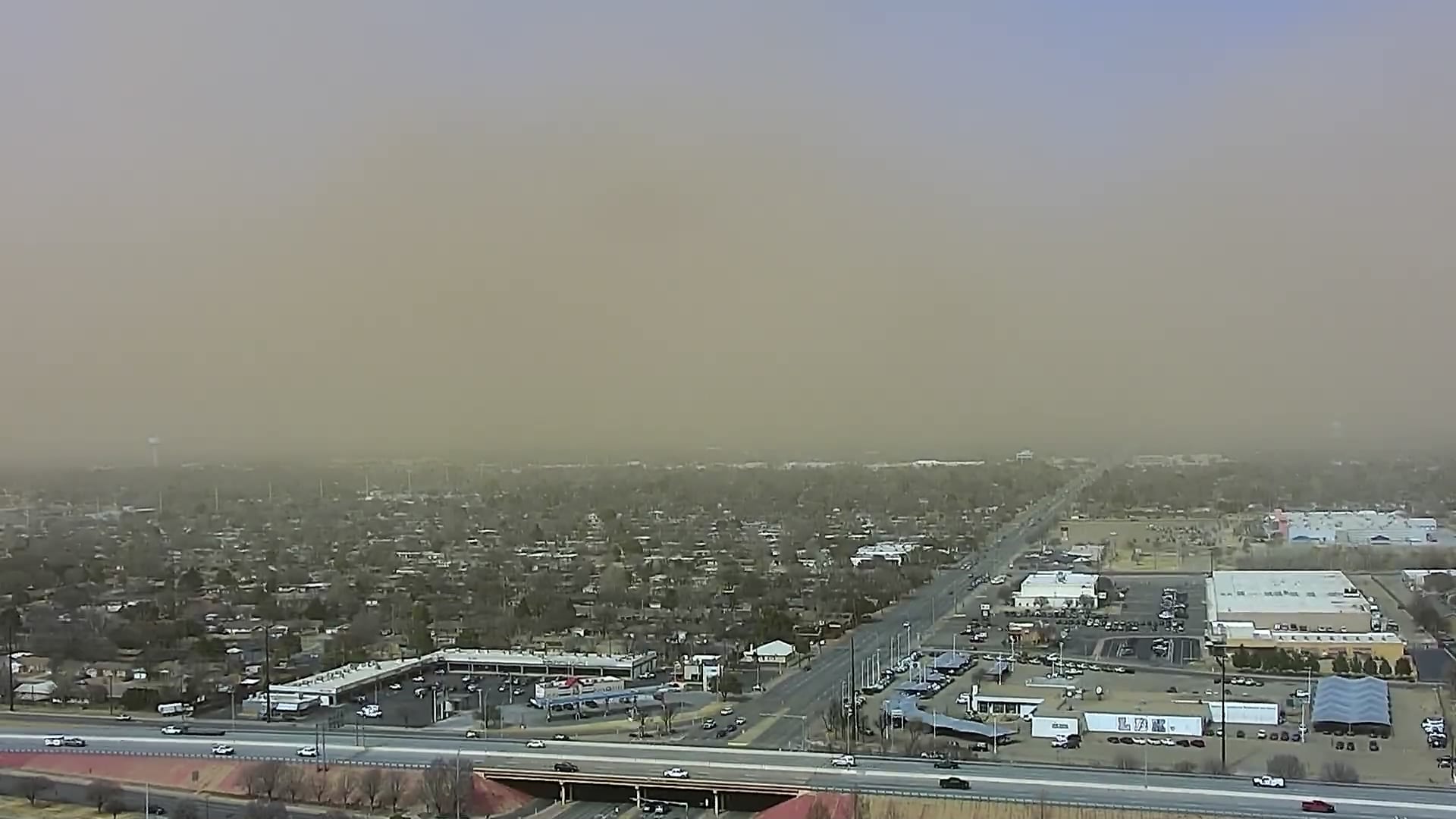 An aerial view of the South Lubbock skyline during a severe dust storm on February 17, 2026, showing a thick, brown layer of blowing dust obscuring the horizon and reducing visibility to approximately one mile.