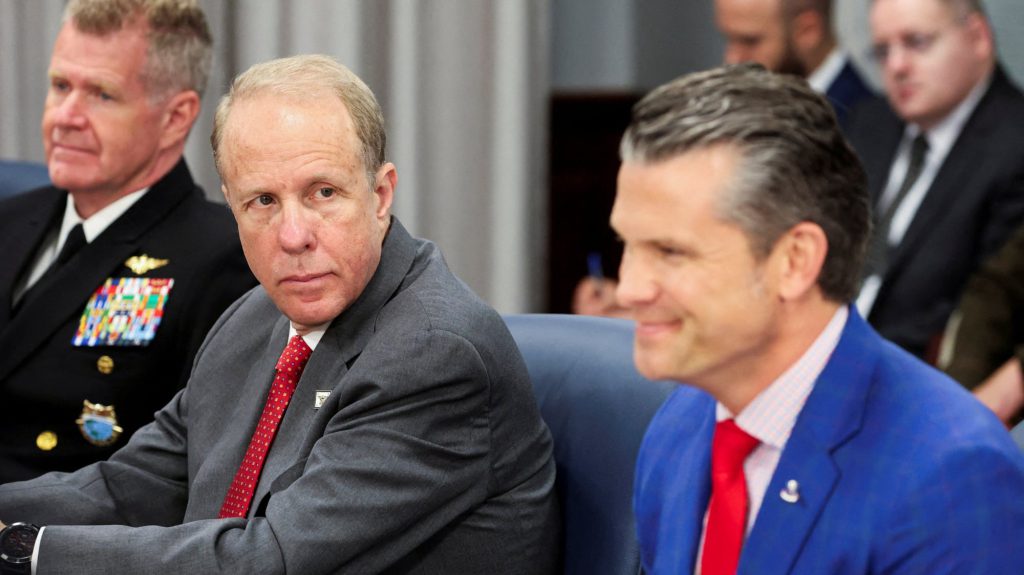 Deputy Secretary of Defense Steve Feinberg (center) looking like he’s calculating his next dividend check while sitting next to a smiling Defense Secretary Pete Hegseth (right) at the Pentagon, proving that the Lubbock "Good Ol' Boy" system scales perfectly to the federal level.