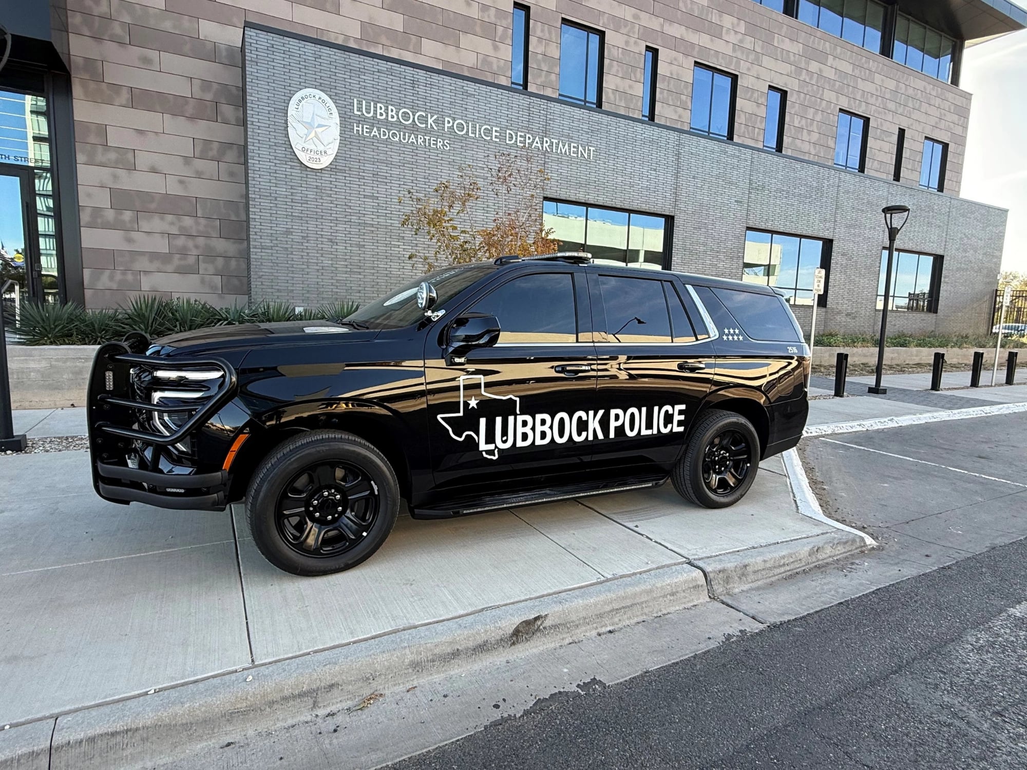 A black Lubbock Police Department SUV parked in front of the modern LPD headquarters building.