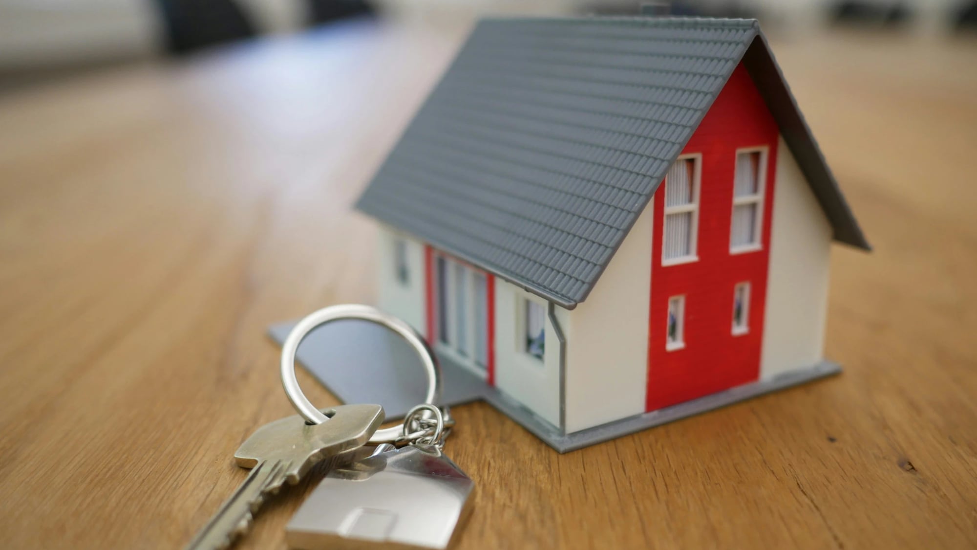 A tiny model house and a set of keys on a wooden table, perfectly capturing the size of the apartment you’re now paying $1,388 a month for in Lubbock.