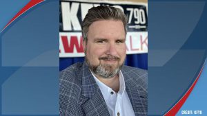 Late radio host Chad Hasty wearing a plaid blazer and smiling in front of a KFYO Newstalk radio banner.