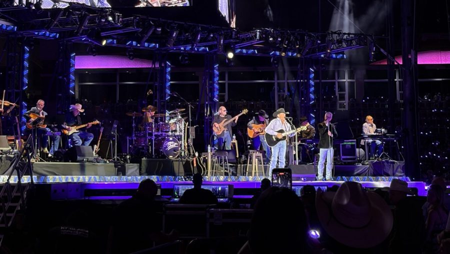 George Strait and his band performing on a massive, neon-lit stage at Jones AT&T Stadium in Lubbock.