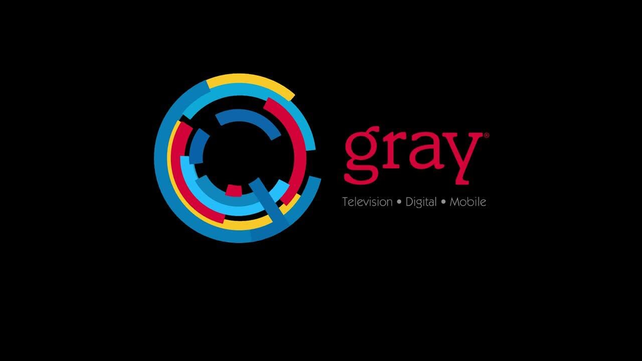 Gray Television logo featuring the brand name in a red serif font and a circular abstract icon composed of interlocking blue, yellow, and magenta segments on a solid black background.