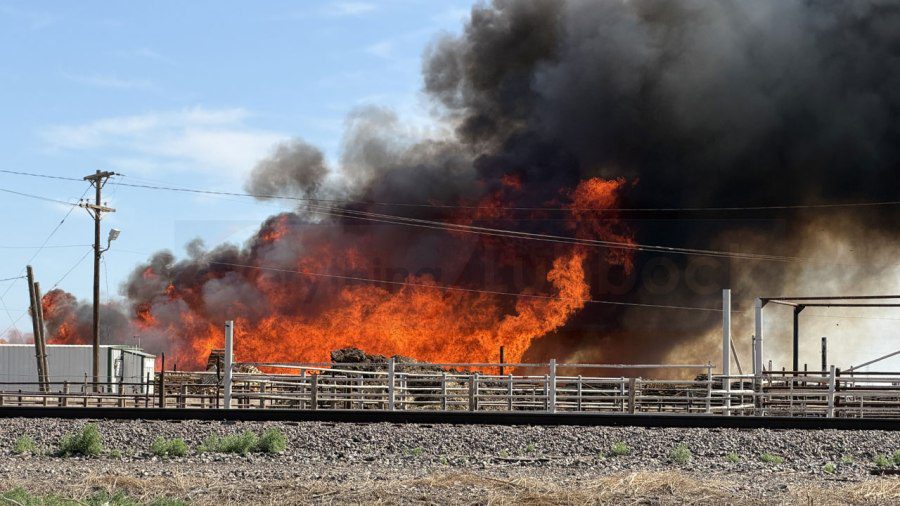 Massive wall of orange flames and thick black smoke billowing from a pallet yard in Lubbock, Texas.