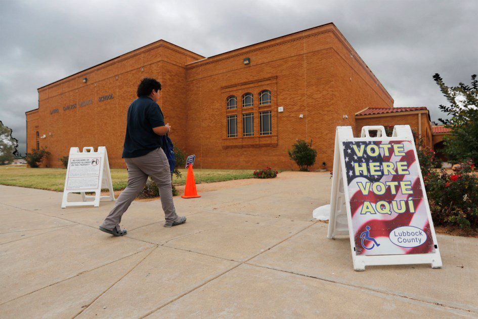 A man walks past a 'Vote Here' sign at Lauro Cavazos Middle School in Lubbock, blissfully unaware that the Department of Homeland Security is currently obsessed with his paperwork.