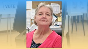 Lubbock County Elections Administrator Roxzine Stinson standing in an office with a "VOTE" sign in the background.