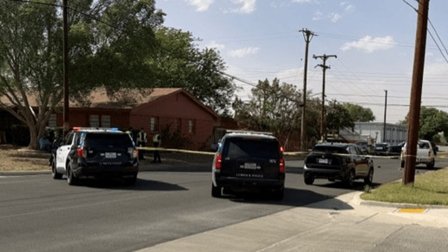 Lubbock police cruisers parked at a residential intersection blocked off by yellow crime scene tape.